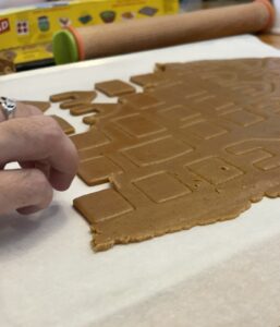 cutting out tiny gingerbread house out of dough