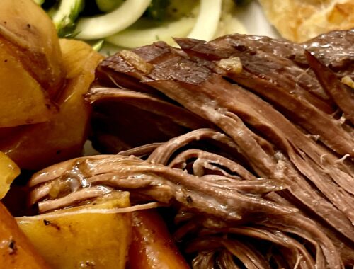 close up of a plate with roast beef, potatoes, carrots, bread and zucchini salad