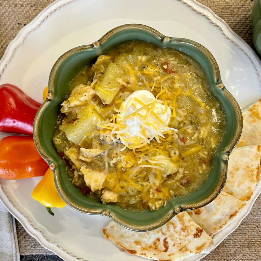 Bowl of Chicken Chile Verde soup with sour cream, cheese, mini peppers and cheese quesadillas