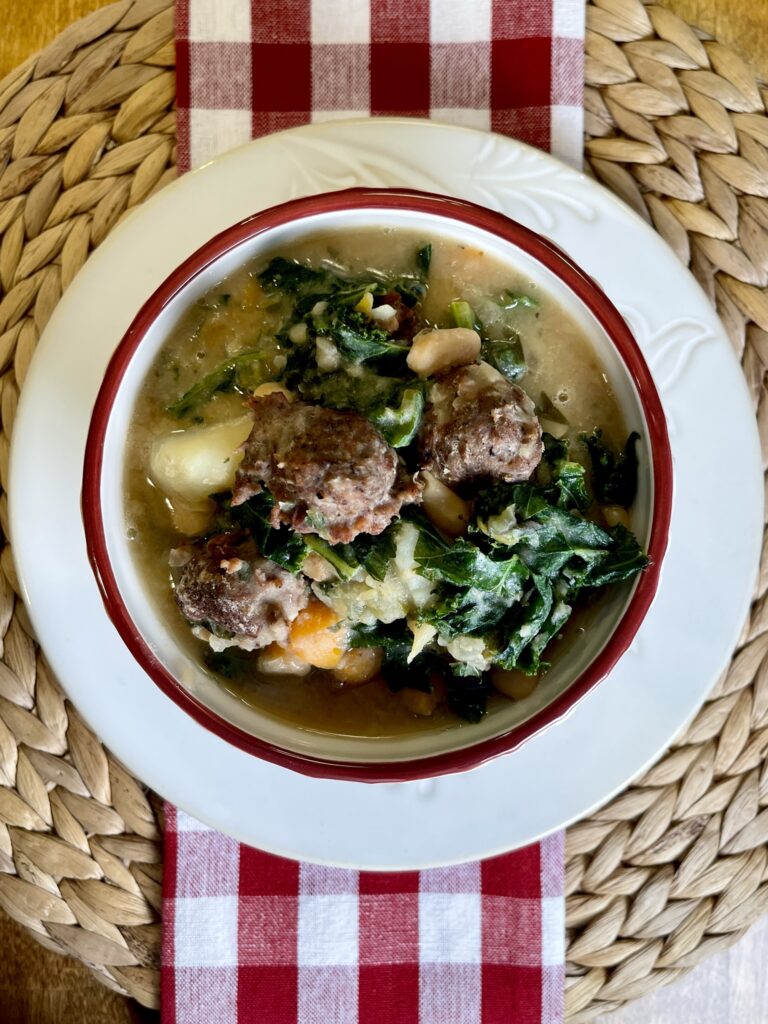 overhead view of bowl with turkey meatball soup on woven mat with red checked napkin