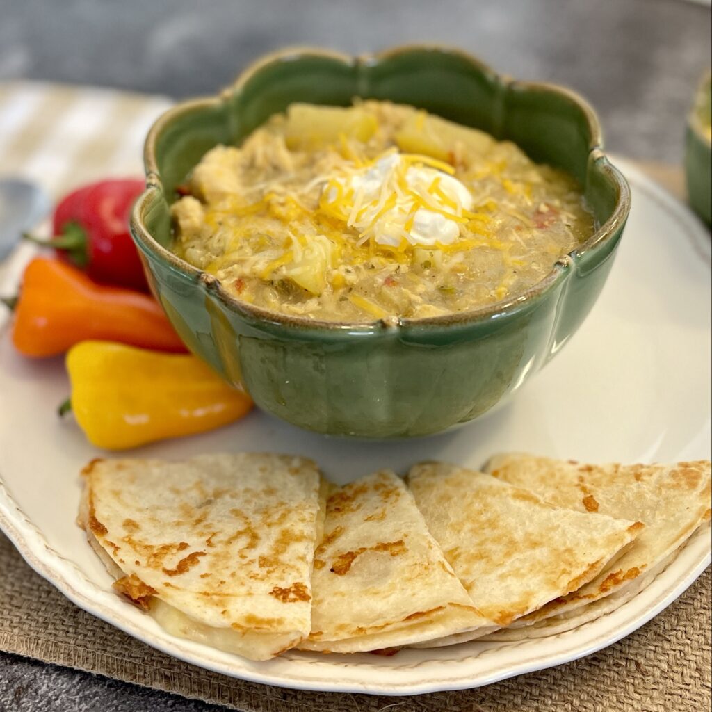Bowl of chicken chile verde soup with mini peppers and cheese quesadillas
