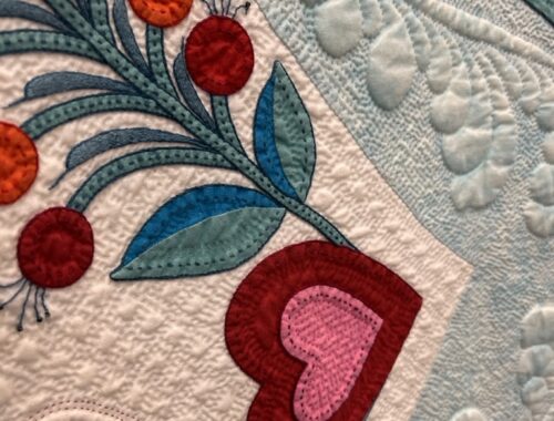 Close up of handiwork winner of the AQS International Quilt Show - red hearts and flowers with blue and white