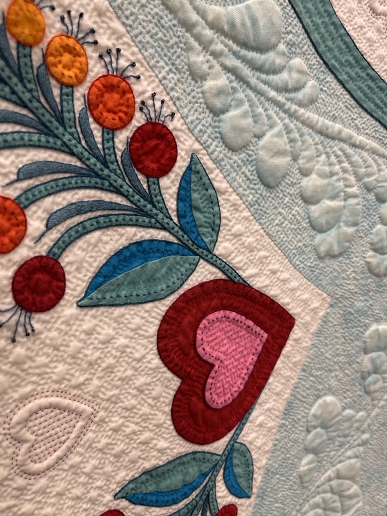 Close up of handiwork winner of the AQS International Quilt Show - red hearts and flowers with blue and white