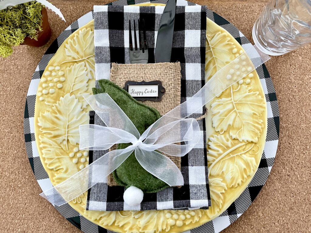 Easter place setting with yellow plate and black and white napkin and burlap silverware holder