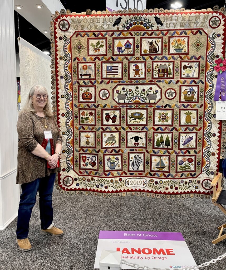 Janet Stone standing in front of her AQS Paducah Quilt Show Best in Show Quilt