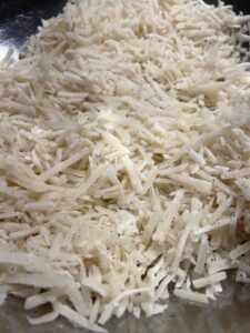 Frozen shredded hash browns added to a large bowl for hash brown casserole recipe