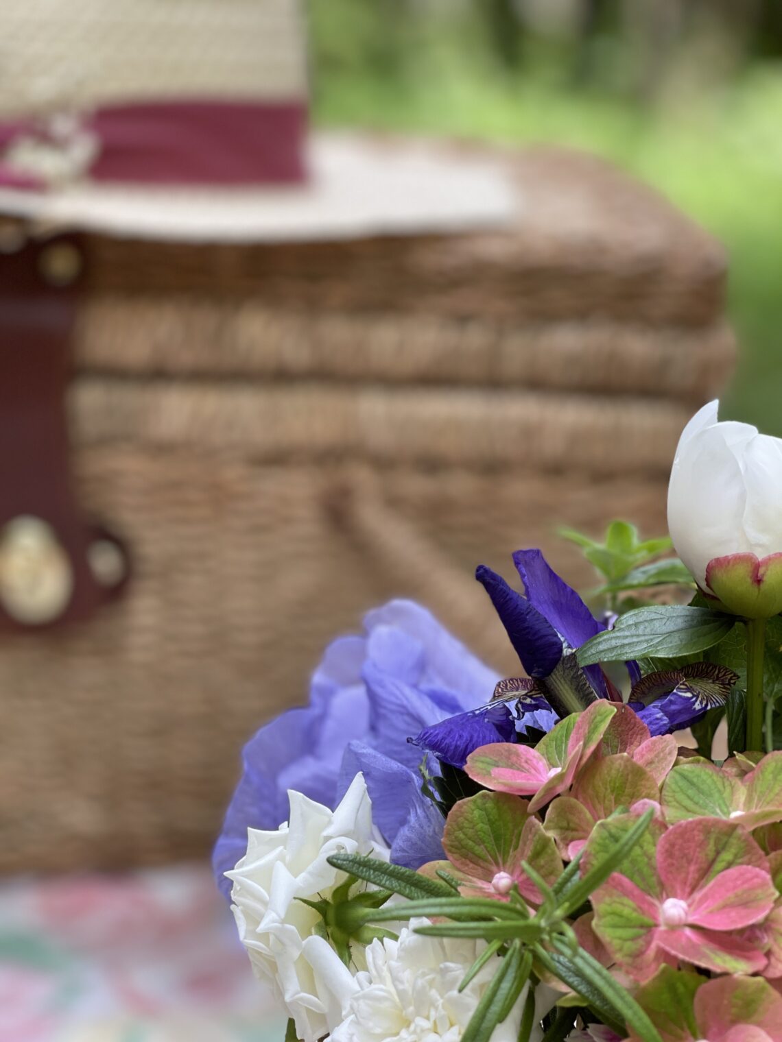 Perennial flowers in front of picnic basket with hat on top
