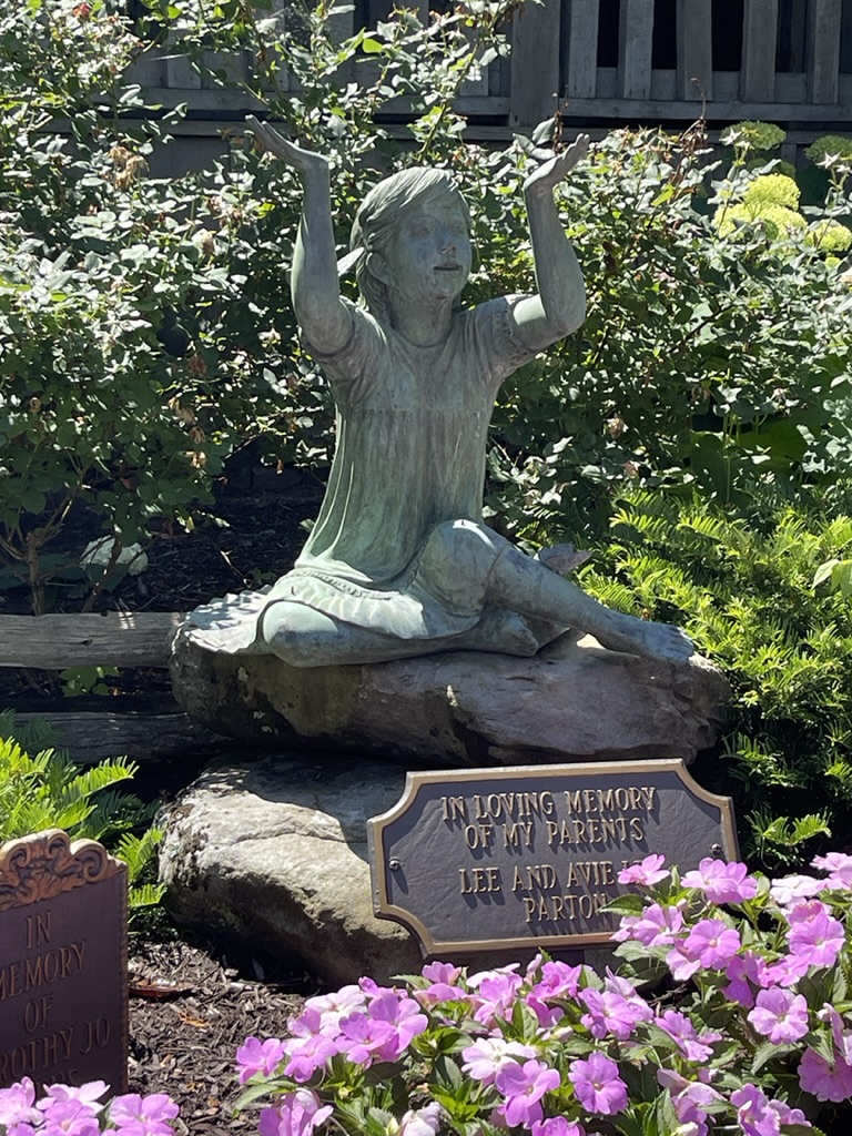 bronze girl statue placed by Dolly in Dollywood in honor of her parents.
