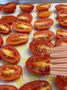 brushing cut cherry tomatoes with infused olive oil with pastry brush