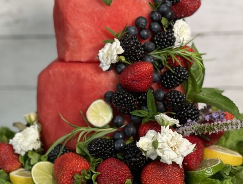 watermelon cake decorated with fruit, roses and rosemary