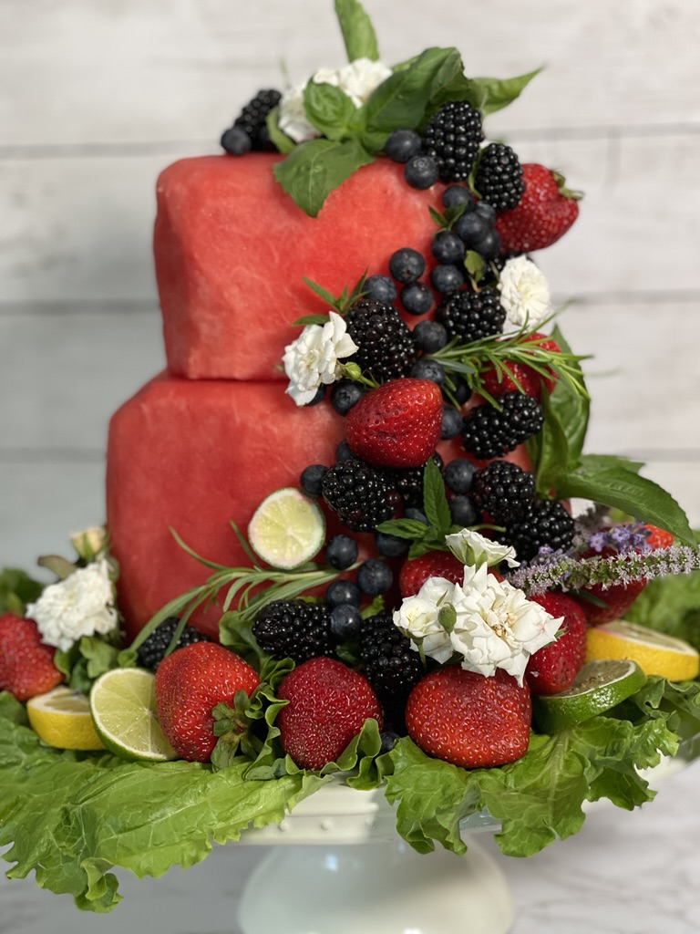 watermelon cake decorated with fruit, roses and rosemary
