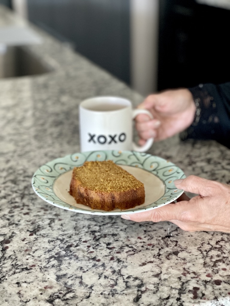 plate with pumpkin bread and hands holding cup
