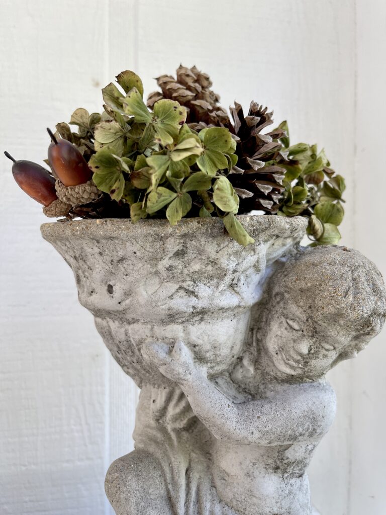 concrete planter filled with hydrangea, pine cones and acorns