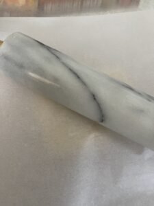 rolling pin on dough with parchment paper on top