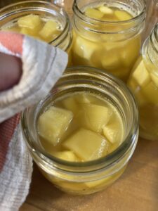 wiping threads and tops off of canning jars with pineapple zucchini