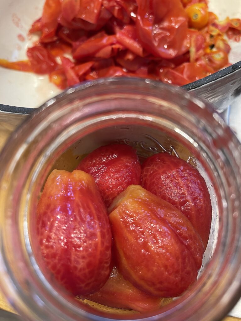 adding whole Roma tomatoes to jars