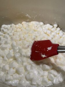 melting marshmallows to create candy corn popcorn balls
