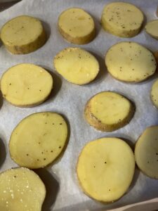 single layer of potato rounds added to parchment paper lined baking sheet for potato skins
