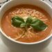 tomato basil soup in bowl with Parmesan cheese and fresh basil