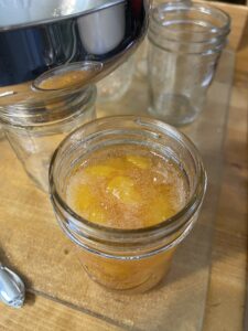 Adding peach jam to jars for canning