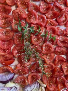 tomatoes for roasting on baking sheet with herbs