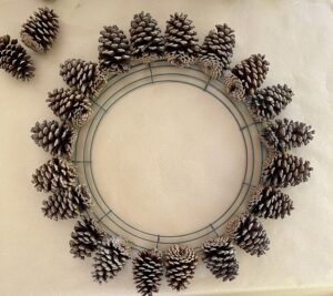 first row of pine cones on metal wreath form