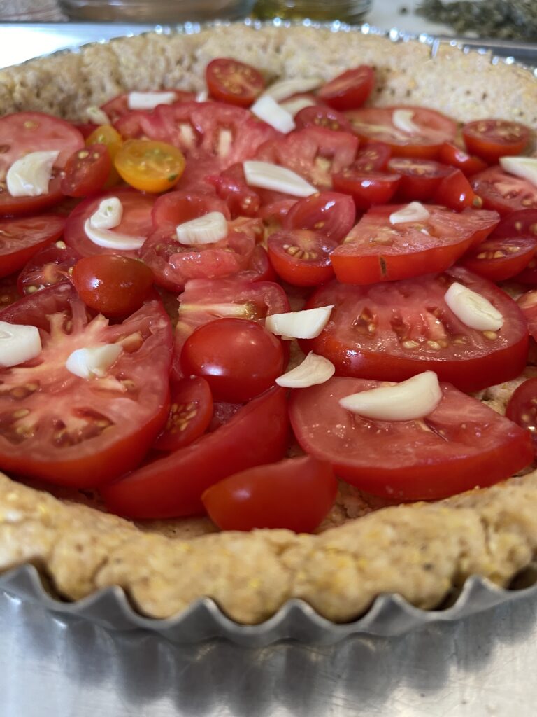 sliced tomatoes and sliced garlic added to tomato tart crust