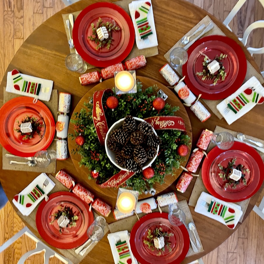 overhead view of Christmas table with red chargers and clear plates