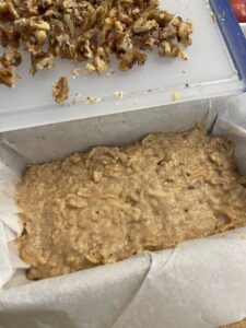 apple bread batter added to parchment paper lined loaf pan