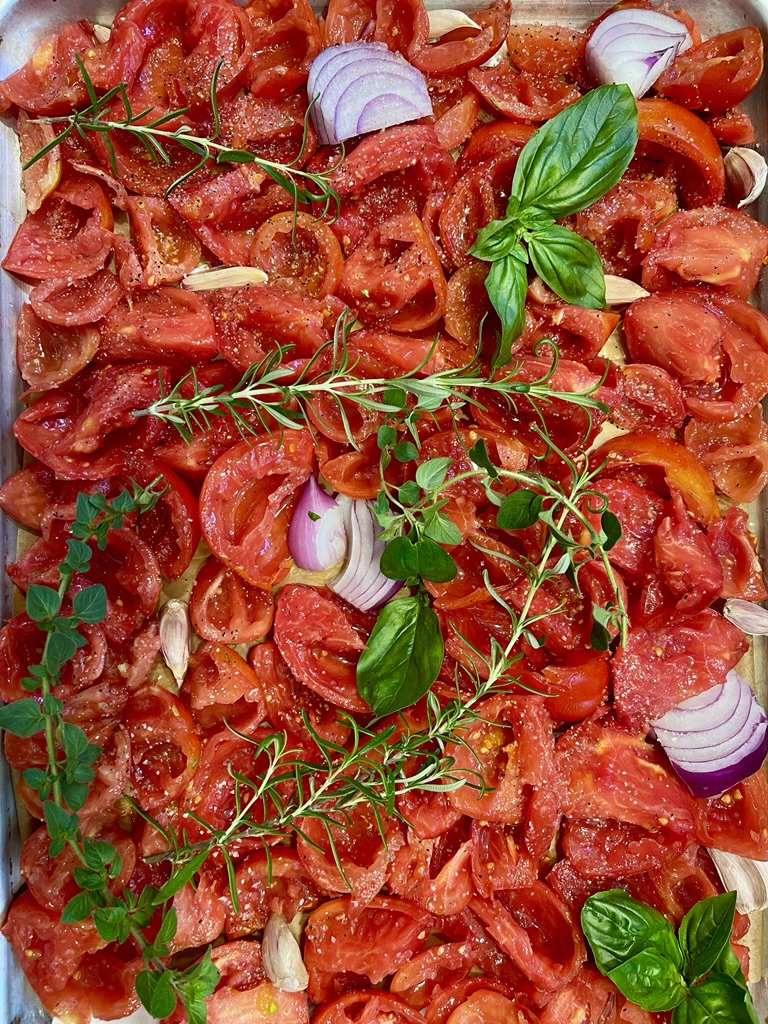 sheet pan of tomatoes, onions, herbs and garlic for roasted tomato sauce