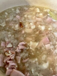 adding liquid and spices to white beans and ham