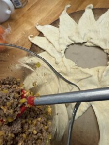 mixing taco seasoned meat and circle of crescent rolls