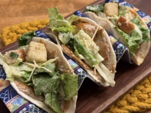 Smashed chicken Caesar salad tacos in holder side view
