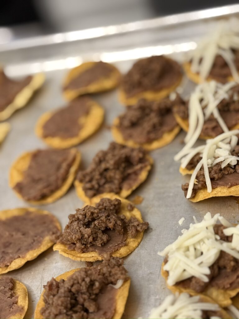 adding refried beans, taco meat and cheese to tiny tacos