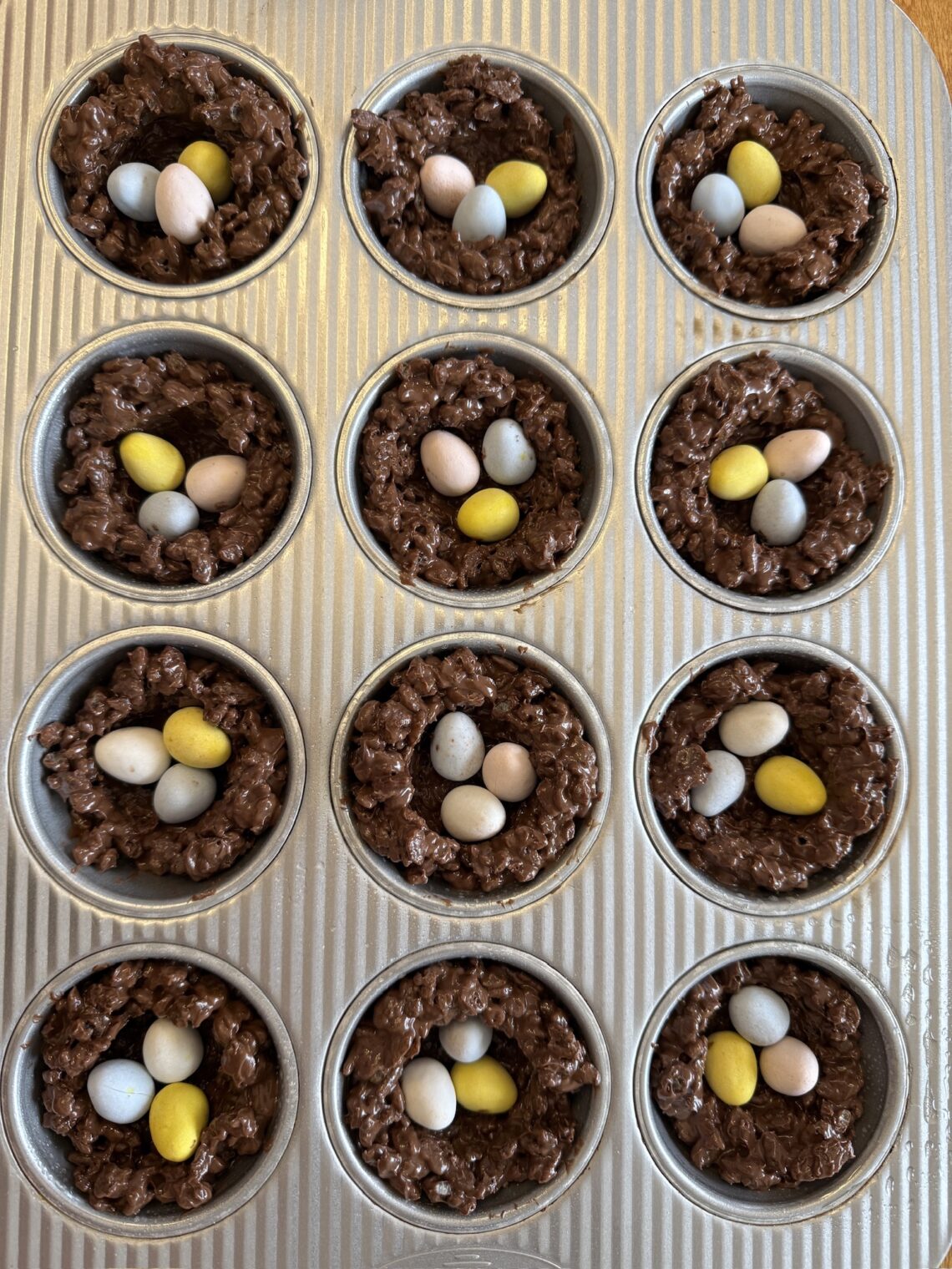 muffin tray filled with Cocoa Rice Krispies bird nests