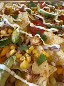 close up of drizzled summer sheet pan BBQ chicken nachos