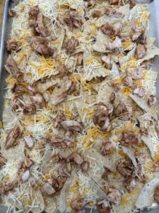 layers of chips, chicken and cheese for the sheet pan nachos