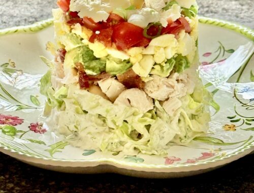 feature stacked Cobb salad on melamine plate