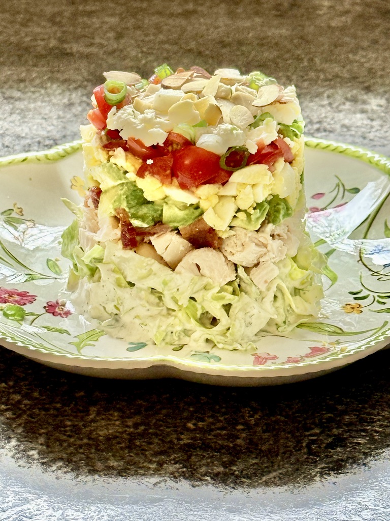 feature stacked Cobb salad on melamine plate